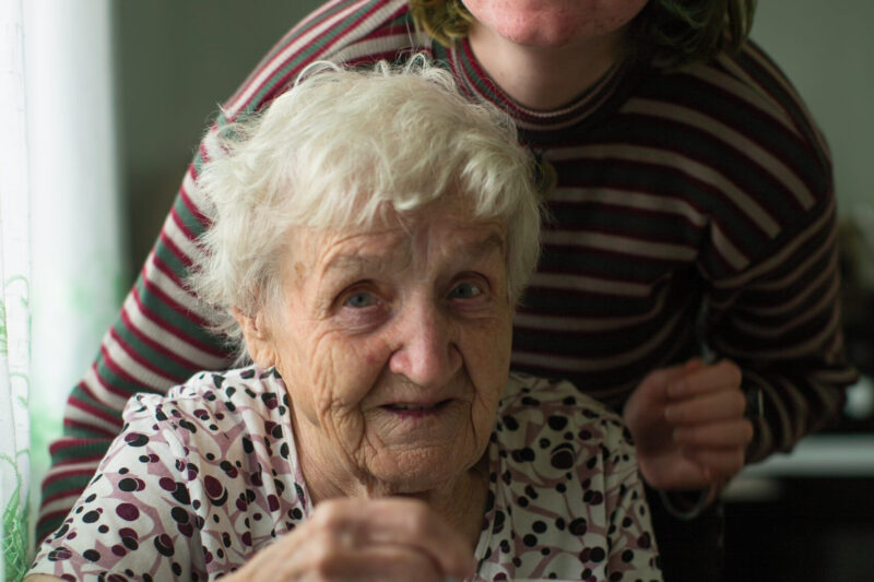 Portrait of old woman with her granddaughter in the kitchen at home.