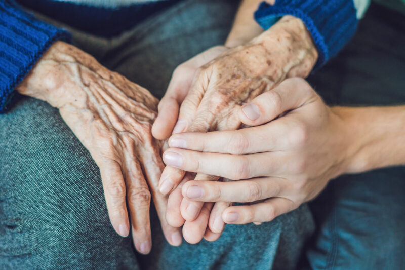 Hands of an old woman and a young man. Caring for the elderly. close up.